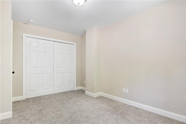 unfurnished bedroom with light colored carpet and a closet