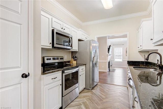 kitchen with sink, stainless steel appliances, light parquet flooring, dark stone countertops, and white cabinets