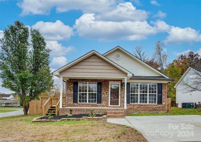 view of front of home with central AC unit, a porch, and a front lawn