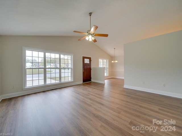 unfurnished living room featuring ceiling fan with notable chandelier, hardwood / wood-style flooring, and lofted ceiling