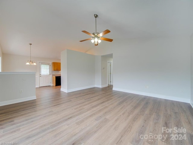 unfurnished living room with ceiling fan with notable chandelier and light hardwood / wood-style floors