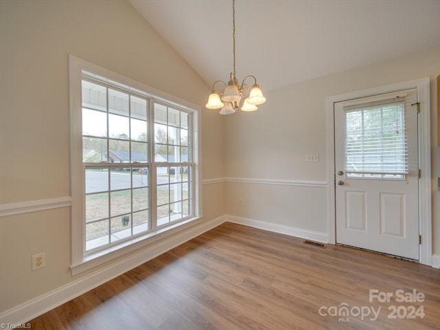 unfurnished dining area featuring light hardwood / wood-style floors, vaulted ceiling, and an inviting chandelier