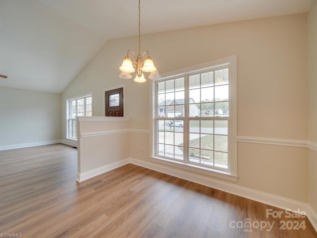 unfurnished dining area featuring lofted ceiling, wood-type flooring, and an inviting chandelier