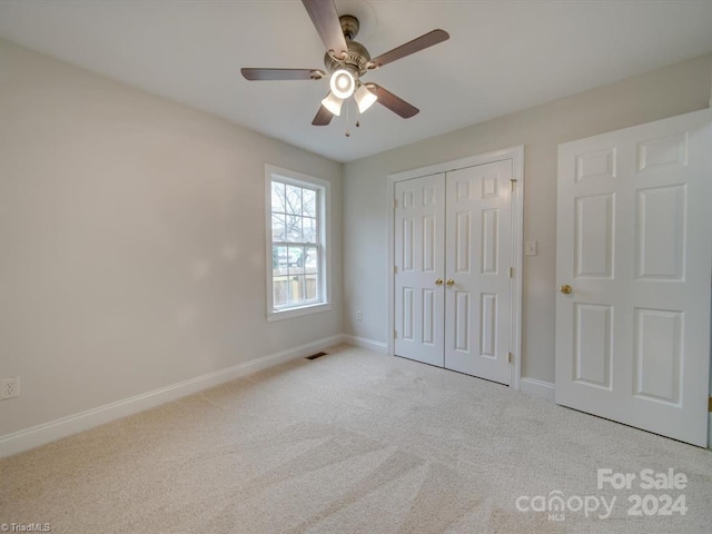 unfurnished bedroom featuring ceiling fan, light carpet, and a closet