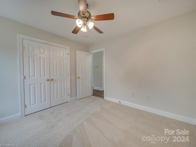 unfurnished bedroom with ceiling fan, light colored carpet, and a closet