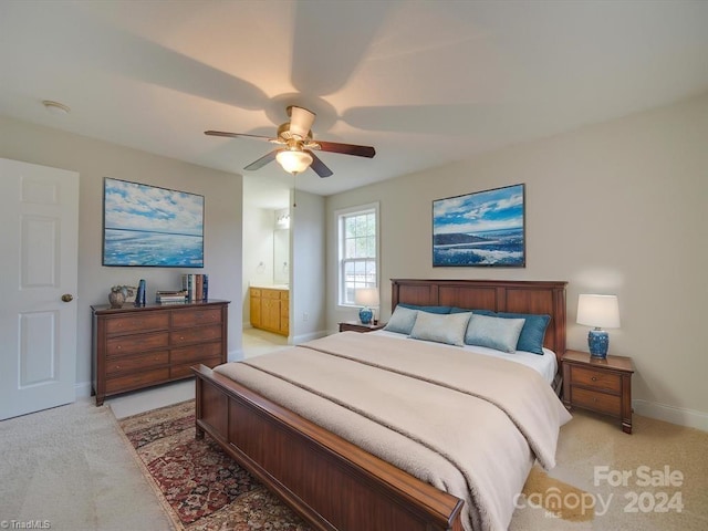 bedroom featuring ceiling fan, light colored carpet, and connected bathroom