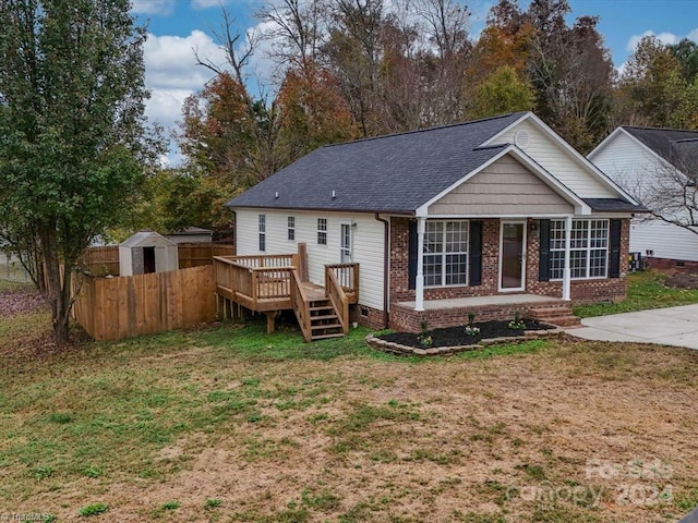 back of property featuring a shed, a yard, and a wooden deck