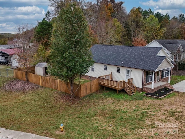 rear view of house featuring a storage unit, a yard, and a wooden deck