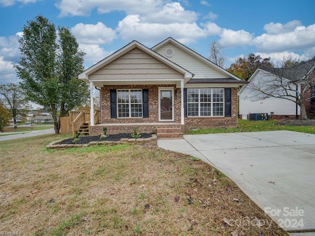 view of front of property with covered porch, a front lawn, and cooling unit