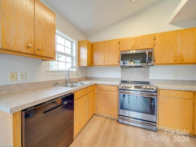 kitchen with sink, stainless steel appliances, vaulted ceiling, and light hardwood / wood-style floors