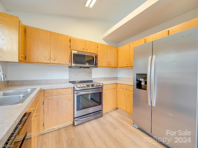 kitchen with sink, stainless steel appliances, vaulted ceiling, and light wood-type flooring