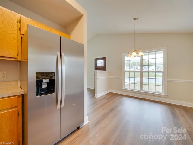 kitchen with stainless steel fridge, light wood-type flooring, vaulted ceiling, pendant lighting, and a chandelier