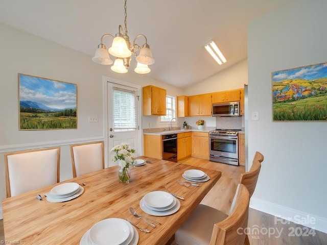 kitchen featuring appliances with stainless steel finishes, vaulted ceiling, sink, pendant lighting, and light brown cabinets