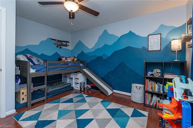 bedroom with ceiling fan, a textured ceiling, baseboards, and wood finished floors