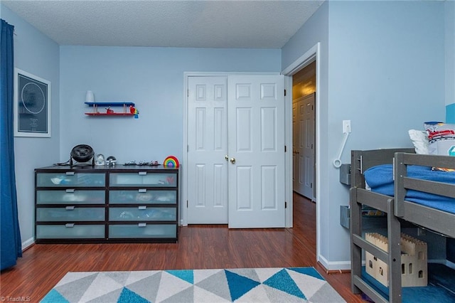 bedroom with a textured ceiling, a closet, baseboards, and wood finished floors