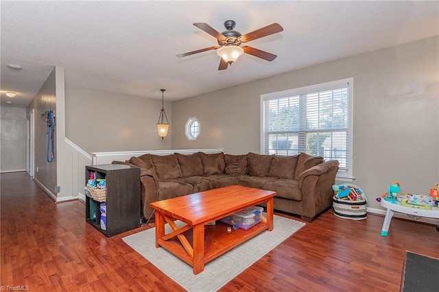 living area with wood finished floors, a ceiling fan, and baseboards