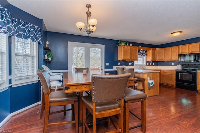 dining room featuring a notable chandelier, baseboards, dark wood-style flooring, and a wealth of natural light