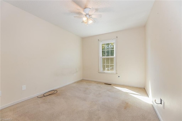 empty room with ceiling fan and light carpet