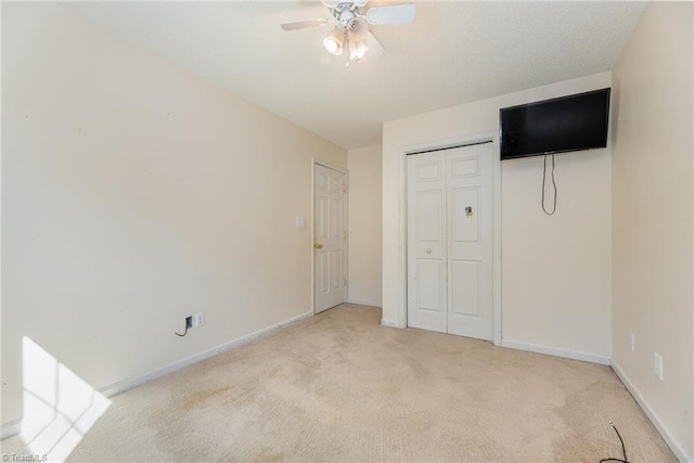 unfurnished bedroom featuring light carpet, a closet, and ceiling fan