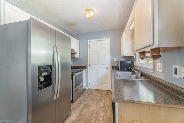 kitchen with appliances with stainless steel finishes, a textured ceiling, light hardwood / wood-style floors, and sink