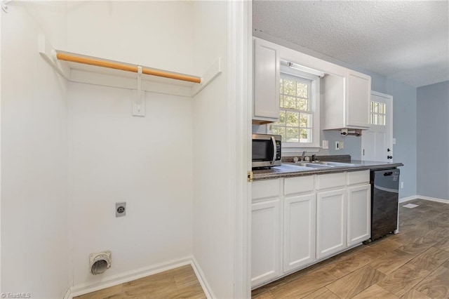 washroom featuring electric dryer hookup, sink, light hardwood / wood-style floors, and a textured ceiling