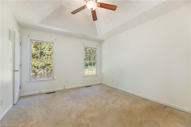 empty room with a wealth of natural light, light colored carpet, and a textured ceiling