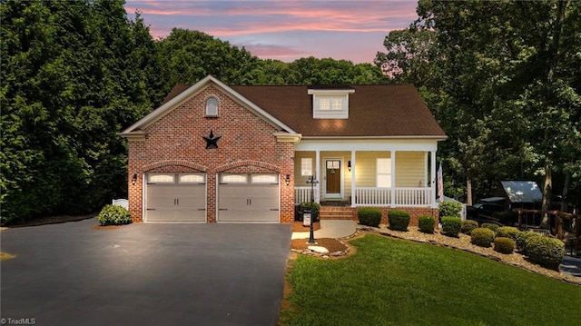 8483 Austin Hill Ln, Tobaccoville, NC 27050 - view of front facade with covered porch, asphalt driveway, brick siding, a front yard, and an attached garage