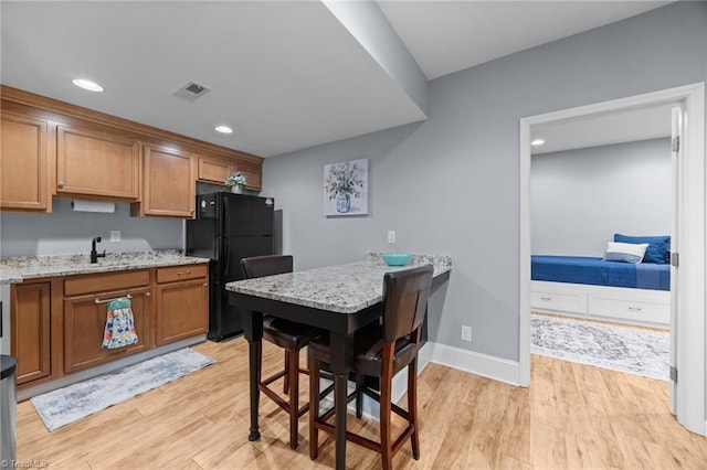 8483 Austin Hill Ln, Tobaccoville, NC 27050 - kitchen featuring freestanding refrigerator, brown cabinets, light wood finished floors, recessed lighting, and light stone counters
