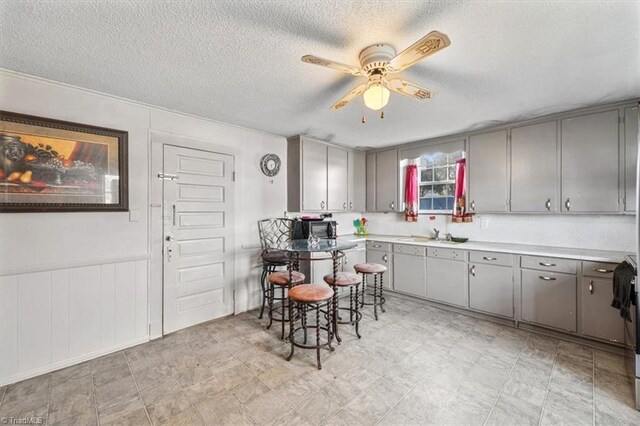 kitchen featuring a textured ceiling, ceiling fan, sink, and gray cabinets