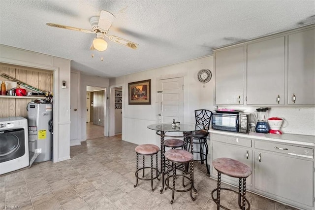 kitchen with a textured ceiling, washer / dryer, ceiling fan, and water heater