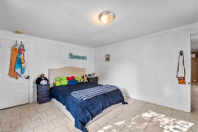 bedroom featuring wood walls, light tile patterned floors, and a textured ceiling