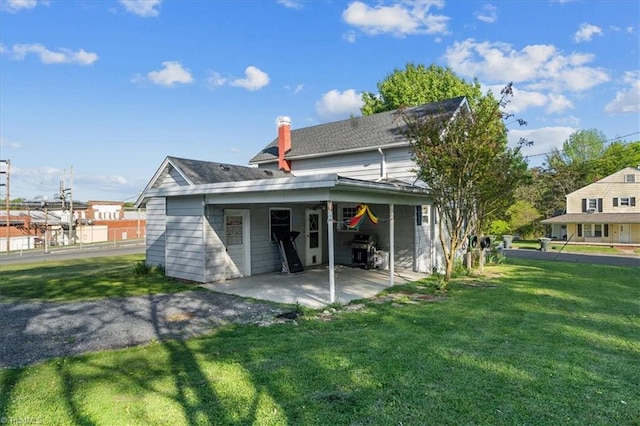 back of house featuring a patio area and a lawn