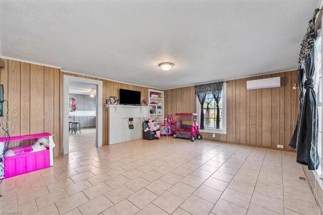 recreation room with wood walls, light tile patterned floors, an AC wall unit, and a textured ceiling