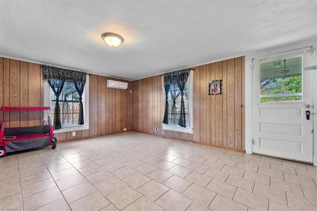 entrance foyer with a textured ceiling, a wall unit AC, and wood walls