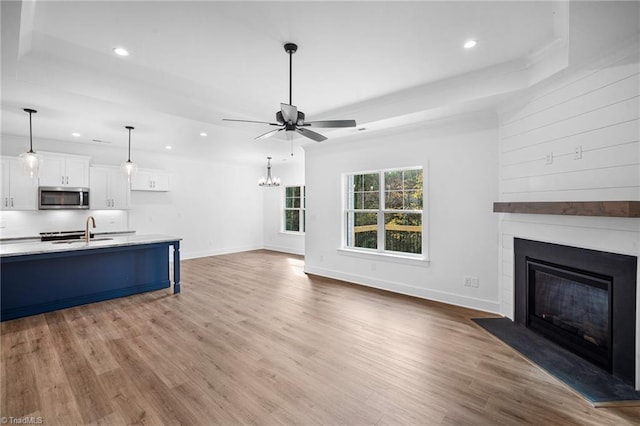 kitchen featuring ceiling fan with notable chandelier, tasteful backsplash, white cabinetry, sink, and hardwood / wood-style flooring