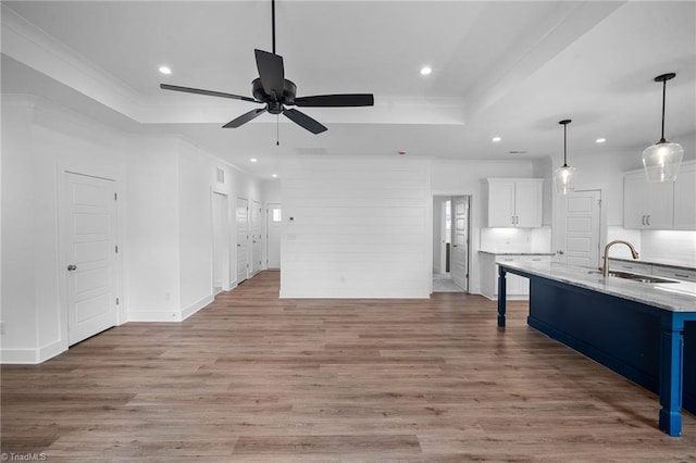 kitchen featuring a breakfast bar, white cabinetry, sink, light hardwood / wood-style floors, and a tray ceiling