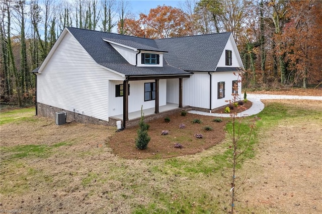 modern farmhouse style home featuring covered porch, a front yard, and central air condition unit