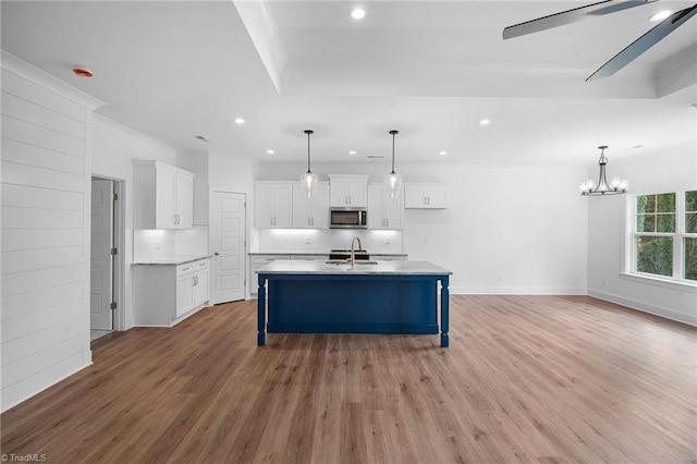 kitchen featuring white cabinetry, a kitchen island with sink, sink, and pendant lighting