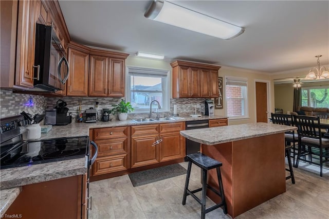 kitchen with black appliances, brown cabinets, a sink, and a breakfast bar area