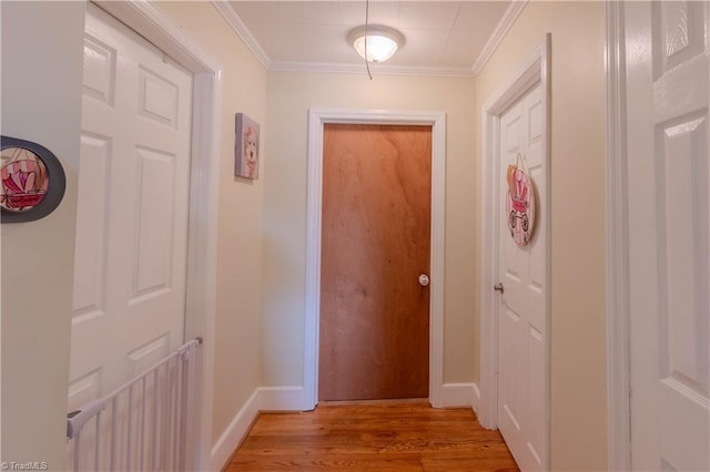 hallway with baseboards, crown molding, and light wood finished floors