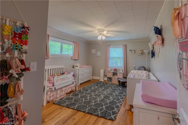 bedroom with light wood-style flooring, crown molding, and ceiling fan
