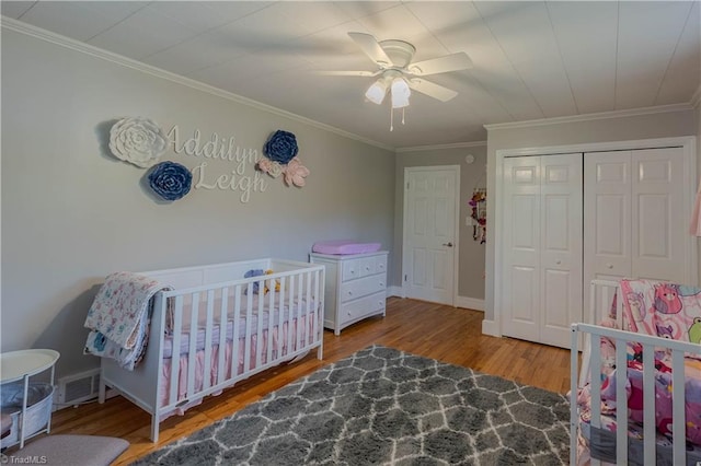 bedroom featuring visible vents, wood finished floors, a closet, ceiling fan, and ornamental molding