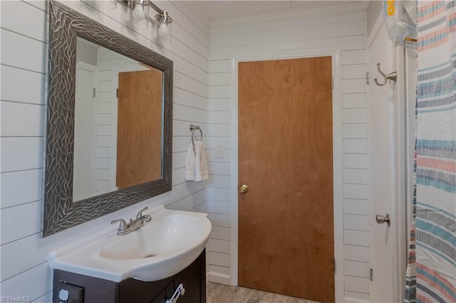 bathroom with wood walls, vanity, curtained shower, and crown molding