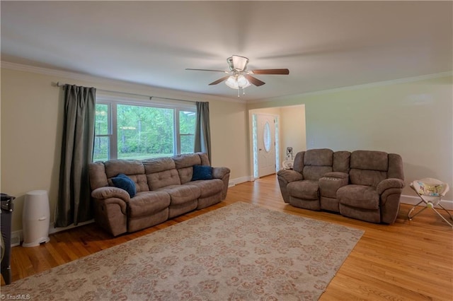 living room featuring ceiling fan, baseboards, ornamental molding, and wood finished floors