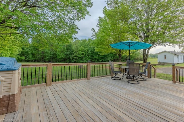 wooden deck featuring a lawn and outdoor dining space