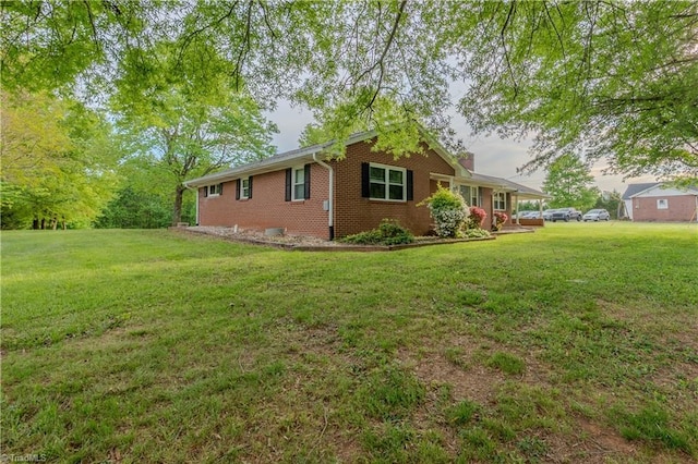 view of side of home with brick siding, a lawn, and a chimney