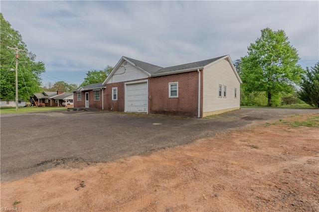 exterior space featuring a garage, driveway, and brick siding
