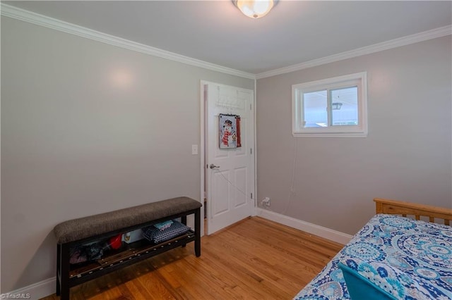 bedroom with baseboards, crown molding, and light wood-style flooring
