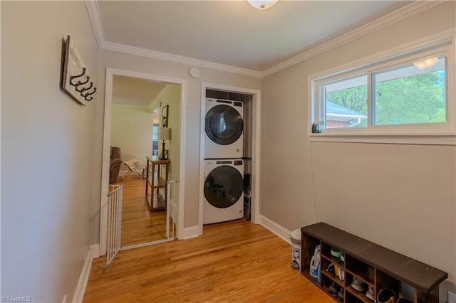 clothes washing area with baseboards, stacked washer / dryer, light wood-style floors, laundry area, and ornamental molding