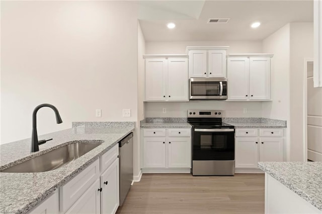 1047 Russell Dr, Winston-Salem, NC 27127 - kitchen with visible vents, light wood-style flooring, appliances with stainless steel finishes, white cabinetry, and a sink